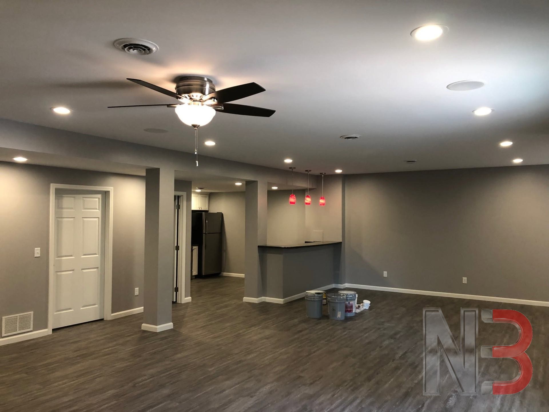 Finished basement living area with recessed lights, ceiling fan and red pendant lights over a bar