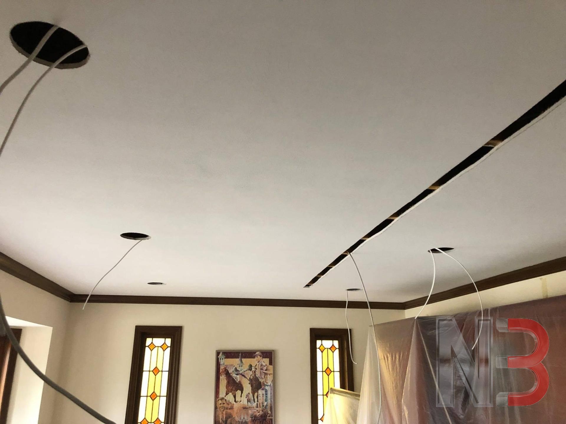 Ceiling holes cut and wire pulled for new recessed lights in an office