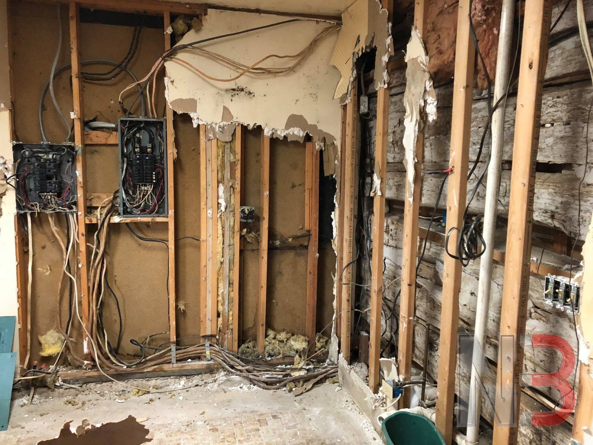 Old electrical panels and outdated wiring exposed in an open wall during demolition