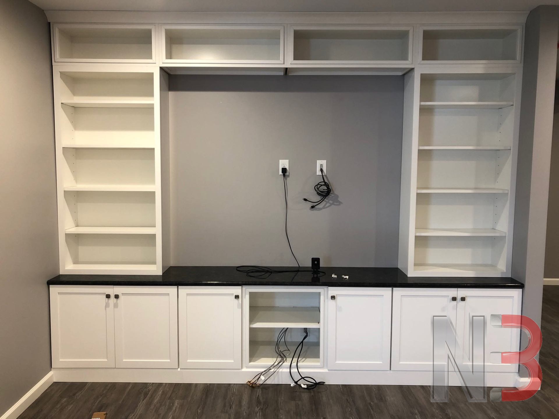 Built-in entertainment wall with power and media outlets installed behind the shelving